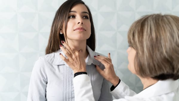 Doctor checking a woman's thyroid