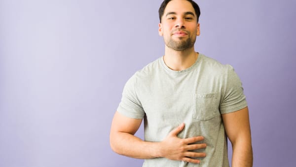 Man holding his stomach in discomfort, illustrating the link between gut health and fatigue