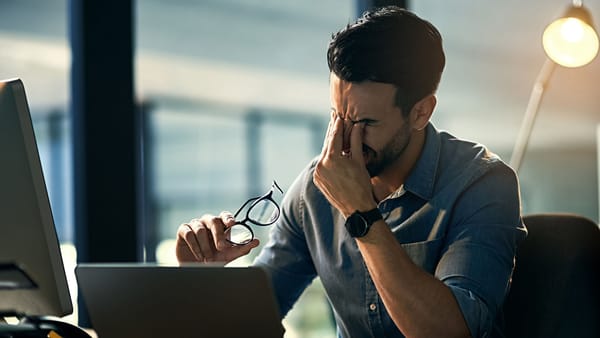 A stressed person holding their face in front of a computer