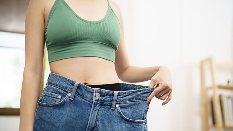 A person wearing a pair of jeans that are too large, indicating weight loss