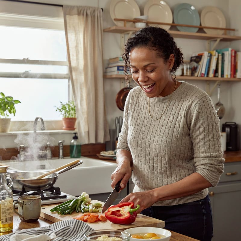 A woman laughing while cooking at home