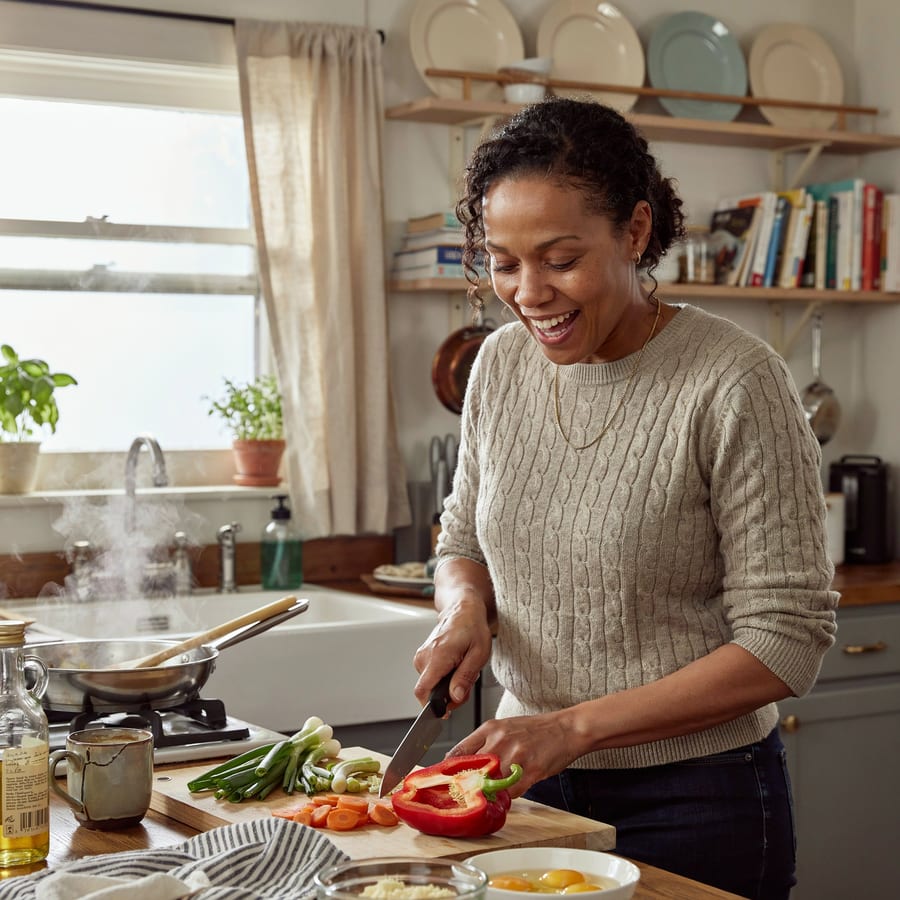 A woman laughing while cooking at home